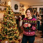 WWE wrestling Cream of the Crop ugly Christmas sweater styled beside Christmas tree — lifestyle shot