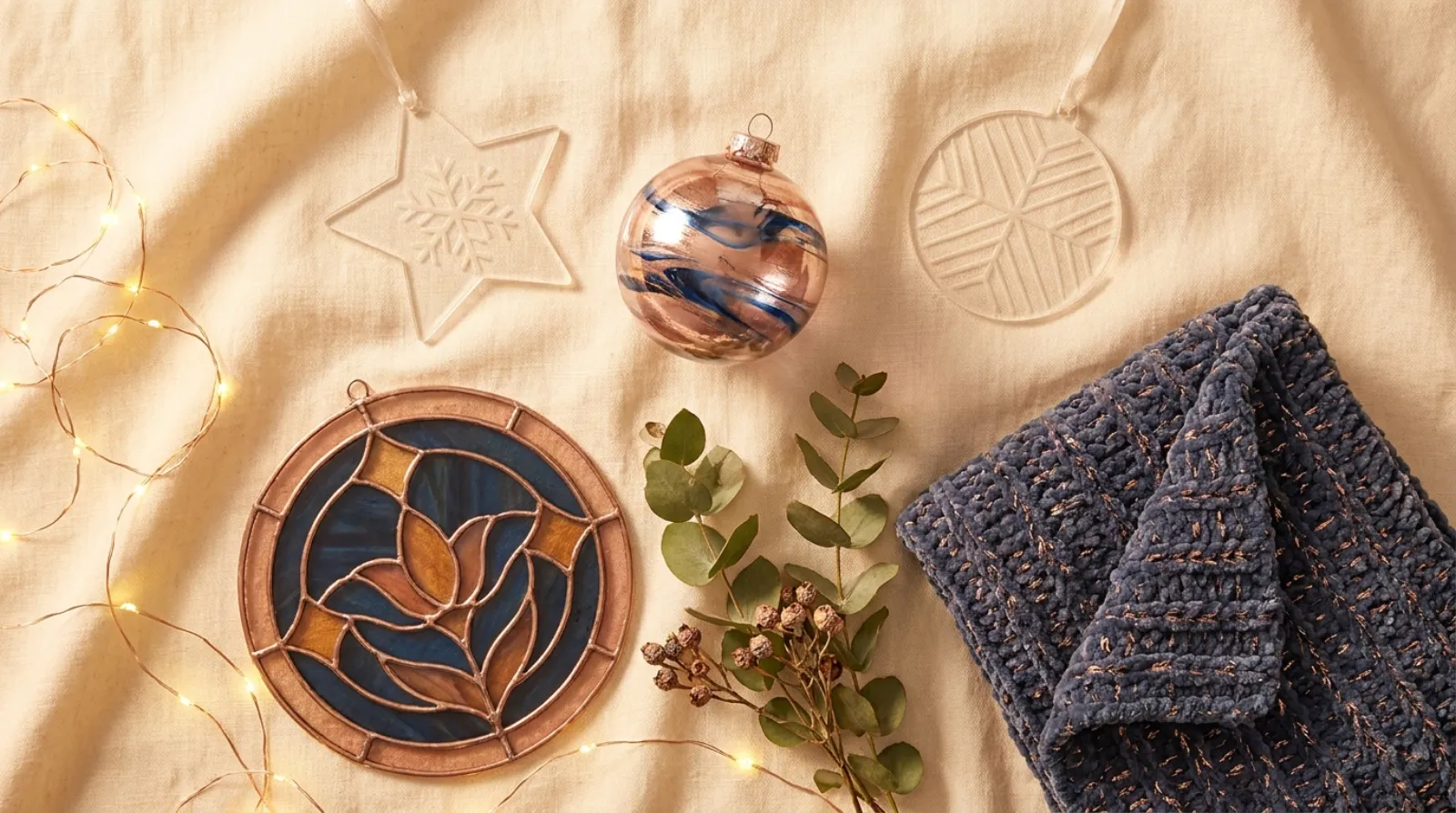 Beauty and the Beast merch flat lay of glass ornament and keepsakes in warm gold and rose tones