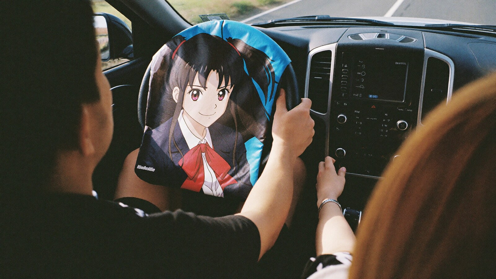 Anime-inspired car steering wheel cover in a social or layered scene with friends