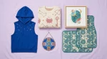 Flat-lay of Disney merch including a sleeveless hoodie, holiday sweater, canvas print, suncatcher, and car floor mats
