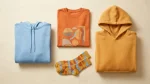 Dragonite merch apparel and socks flat lay in warm orange and amber tones