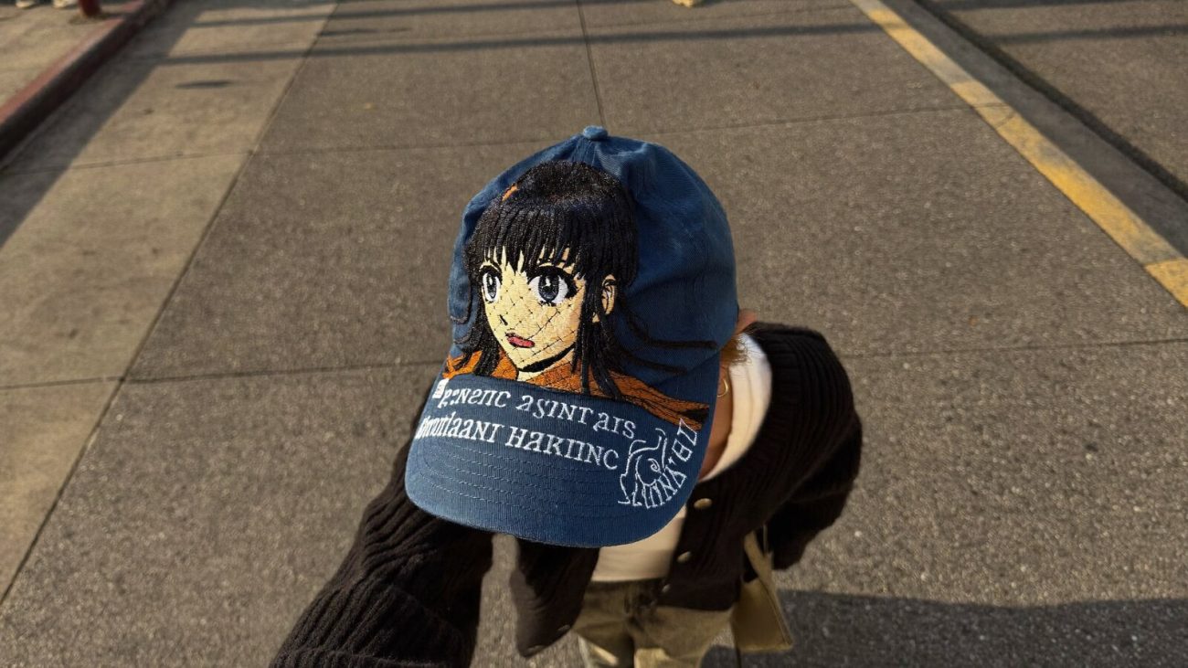 Person wearing an anime-inspired embroidered baseball cap in an editorial scene