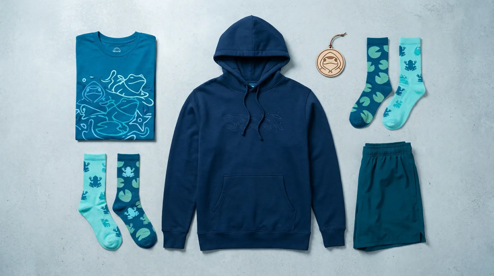 Blue and teal Greninja merch tee, hoodie, gym shorts, and ornament Pokemon apparel flat-lay