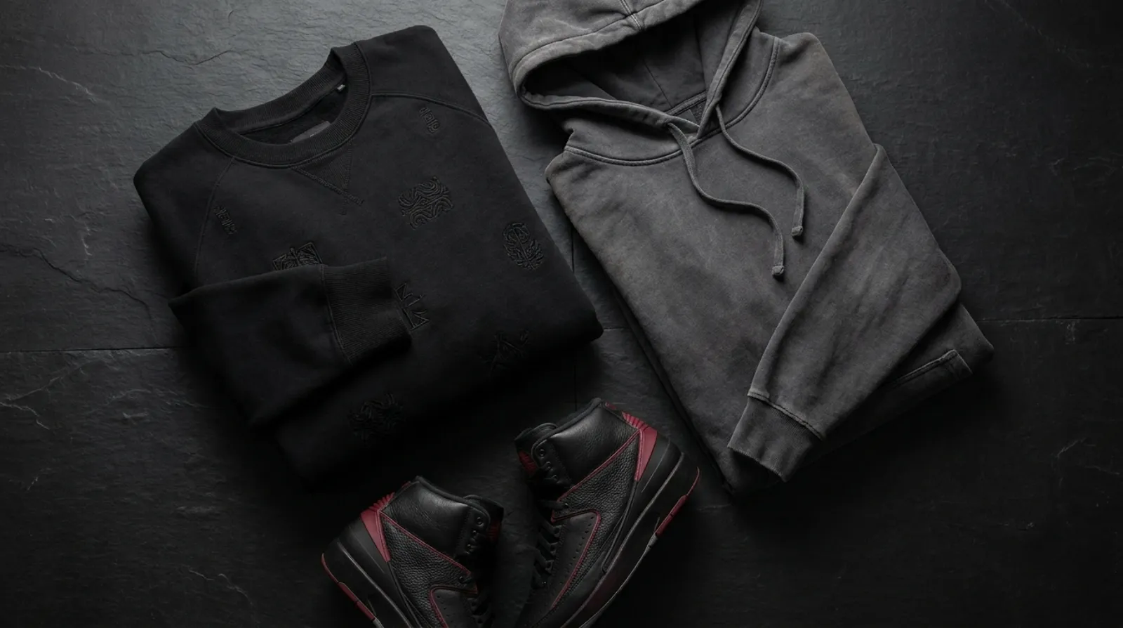 Flat-lay of dark Uchiha Itachi merch including black embroidered sweatshirt, vintage hoodie, and high-top sneakers