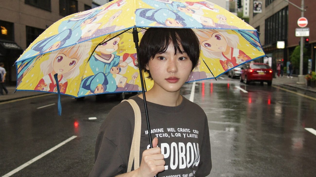 Person wearing an anime-inspired umbrella in an editorial scene