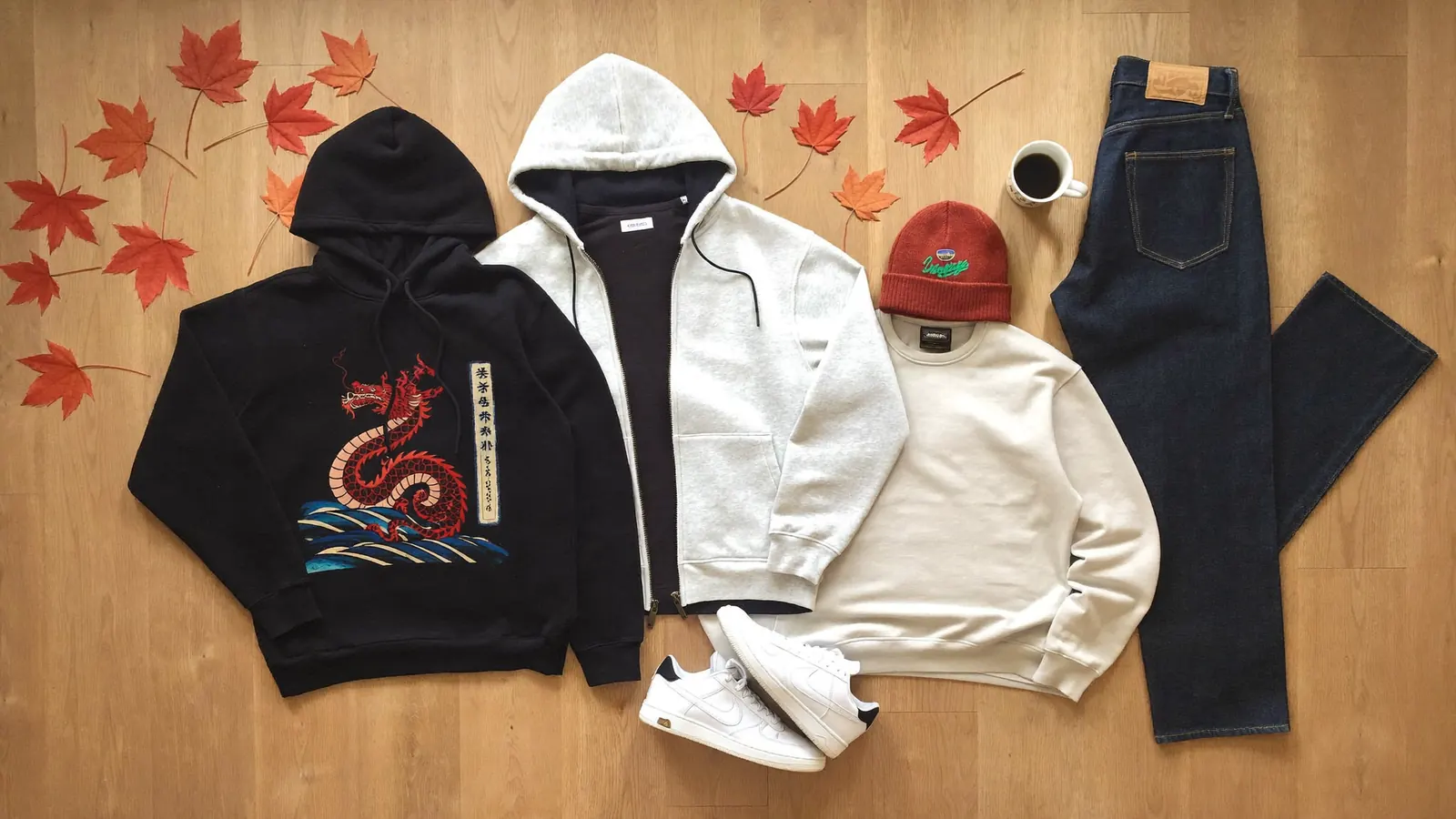 Flat lay of a fall outfit with an anime dragon hoodie, zip hoodie, crewneck sweatshirt, jeans, beanie and sneakers